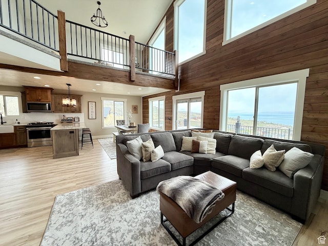 660 N Cambry Dr, Garden City, UT 84028 - living room with wooden walls, a high ceiling, light wood-style flooring, and a chandelier
