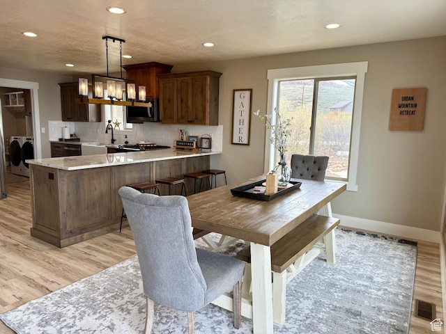 660 N Cambry Dr, Garden City, UT 84028 - dining area featuring an inviting chandelier, washer and clothes dryer, light wood-style flooring, and recessed lighting