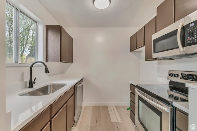 4238 W Old Miller Ct S, Salt Lake City, UT 84118 - kitchen featuring a sink, light countertops, baseboards, light wood-style floors, and stainless steel appliances