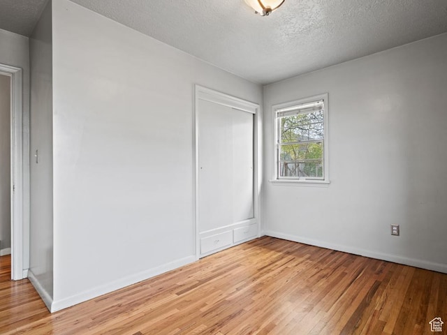 1417 E Binford St, Ogden, UT 84401 - unfurnished bedroom with light wood-type flooring, a textured ceiling, baseboards, and a closet