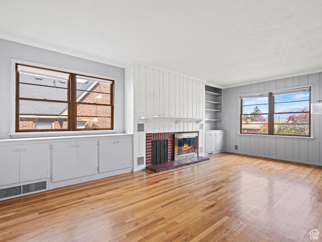 1417 E Binford St, Ogden, UT 84401 - unfurnished living room with visible vents, crown molding, a brick fireplace, light wood-type flooring, and built in shelves
