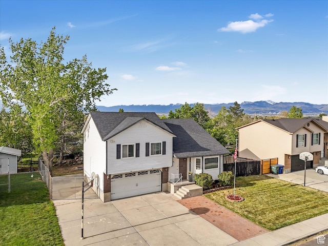 split level home with a garage, fence, concrete driveway, and a front lawn