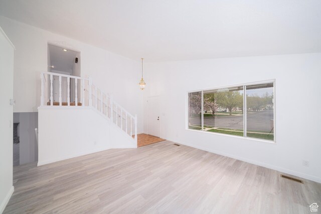 1720 N 1850 E, North Logan, UT 84341 - unfurnished living room with visible vents, baseboards, wood finished floors, and stairway