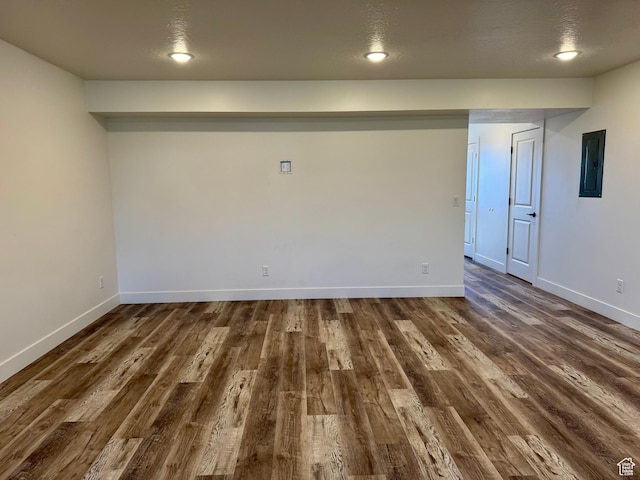 spare room featuring dark wood-style flooring, baseboards, and electric panel