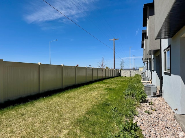 view of yard featuring a fenced backyard and central AC