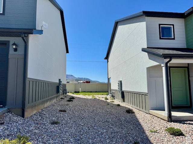view of home's exterior with fence, a mountain view, and stucco siding