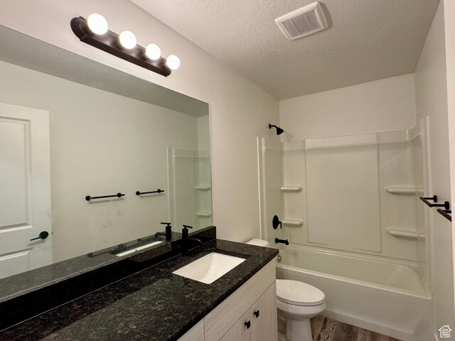 bathroom with visible vents, vanity, wood finished floors, toilet, and a textured ceiling