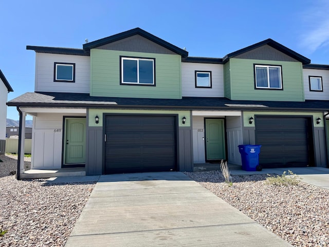 townhome / multi-family property featuring a garage, roof with shingles, and driveway