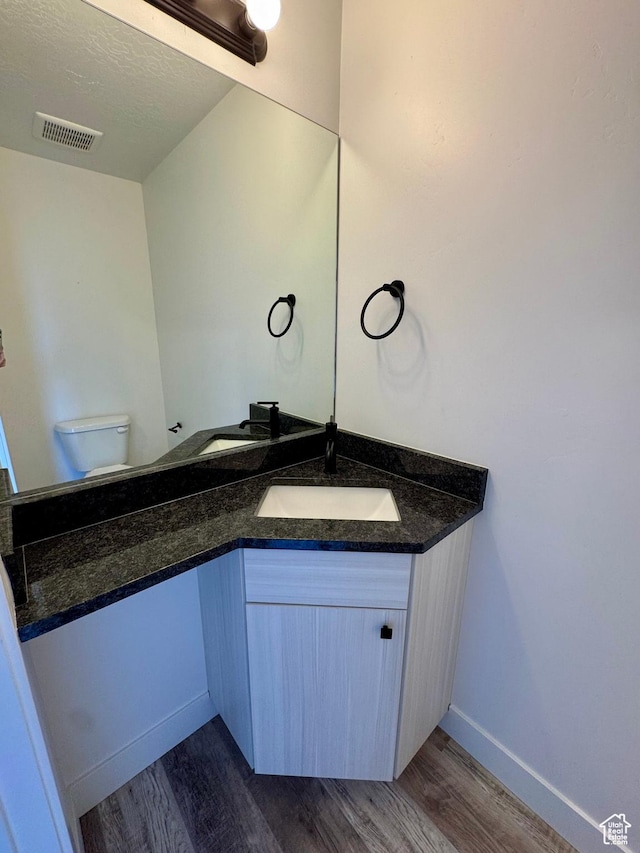 bathroom with vanity, visible vents, wood finished floors, toilet, and baseboards