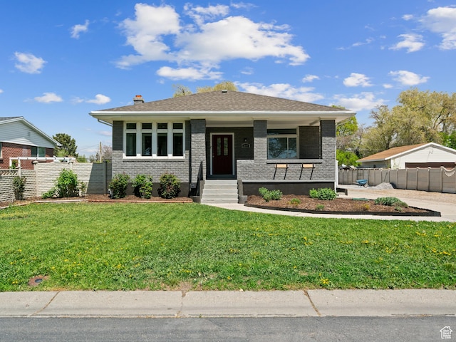 view of front facade with brick siding, fence, and a front yard
