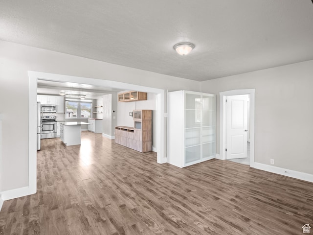 3084 W 3875 S, West Valley City, UT 84119 - unfurnished living room featuring baseboards, a chandelier, and wood finished floors