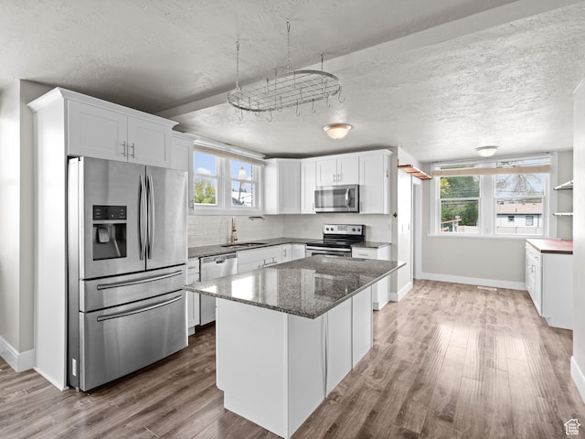 3084 W 3875 S, West Valley City, UT 84119 - kitchen with wood finished floors, dark stone counters, white cabinetry, a sink, and appliances with stainless steel finishes