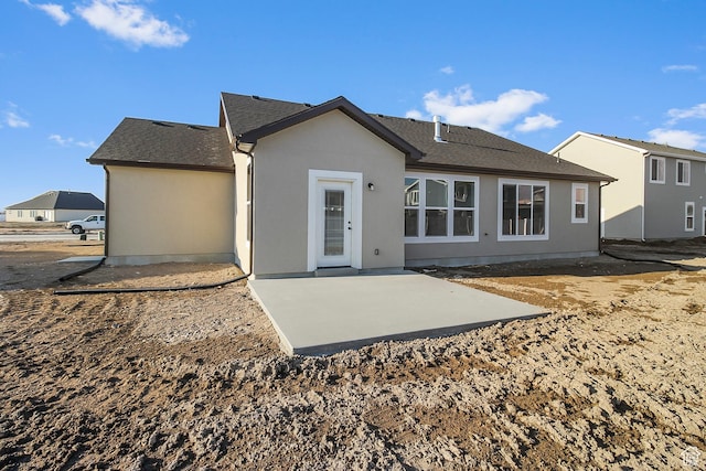 rear view of house featuring a patio, a shingled roof, and stucco siding