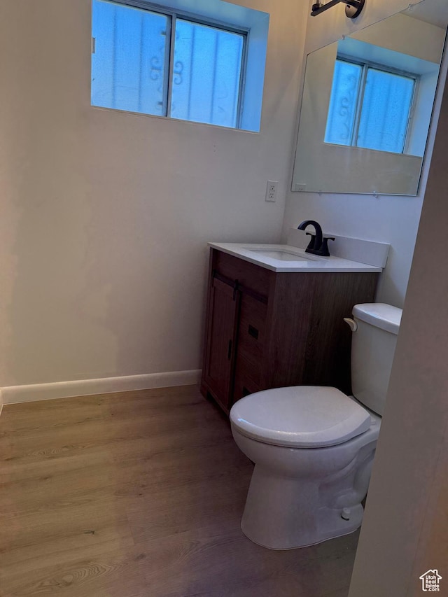 bathroom featuring baseboards, vanity, toilet, and wood finished floors