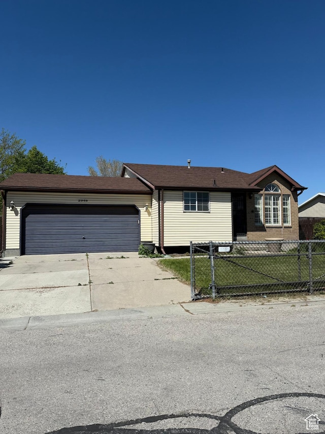 ranch-style house with an attached garage, fence private yard, and concrete driveway