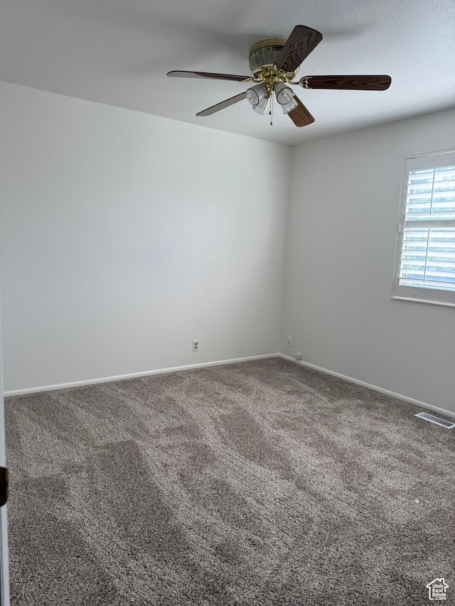 carpeted spare room with a ceiling fan, baseboards, and visible vents