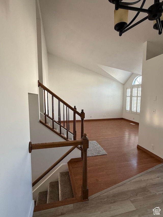 stairs with baseboards, wood finished floors, and vaulted ceiling