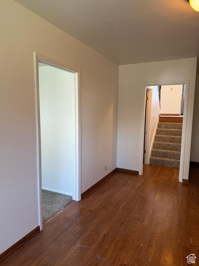 spare room with stairway, baseboards, and wood finished floors
