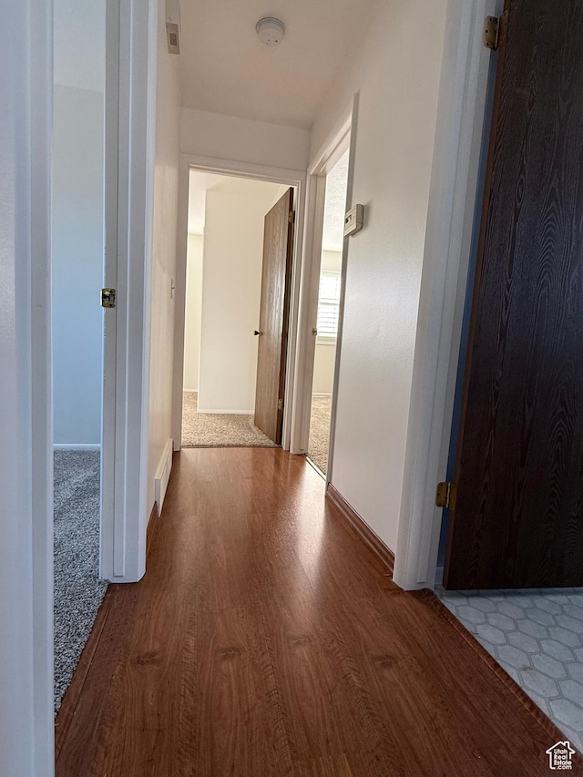 hall with baseboards, visible vents, and wood finished floors