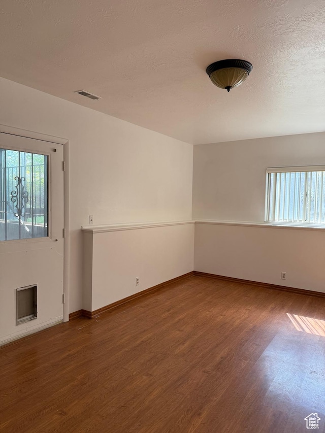 empty room featuring baseboards, wood finished floors, and visible vents