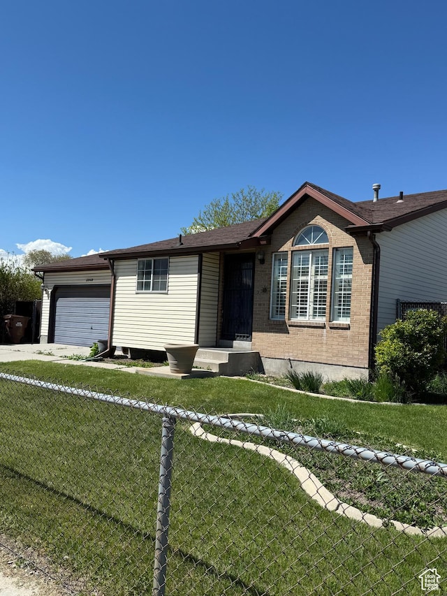 ranch-style house with an attached garage, a front lawn, and brick siding