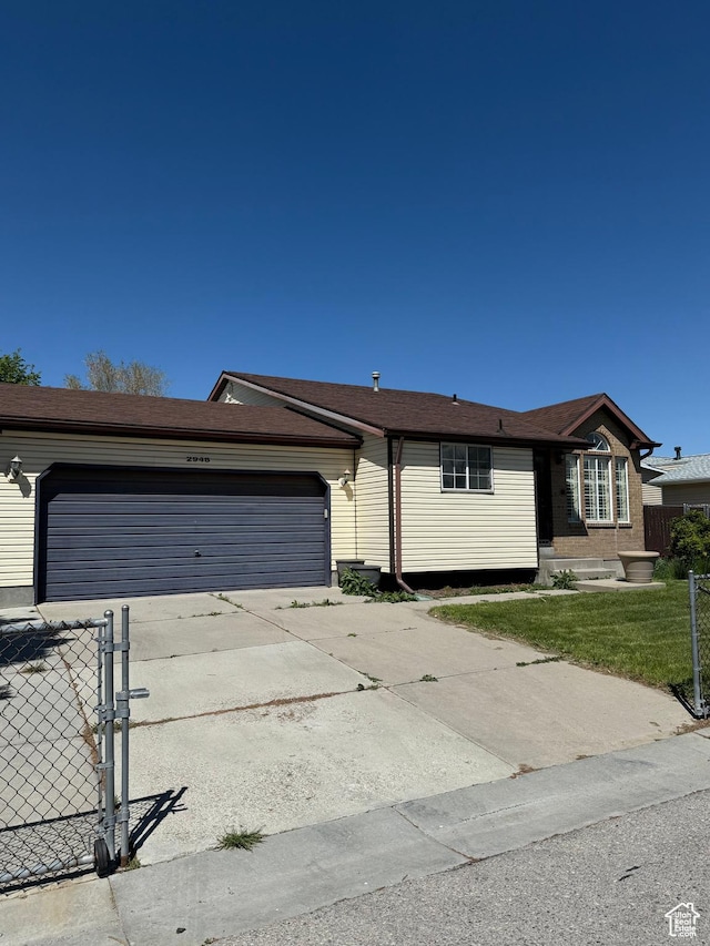 ranch-style house featuring fence, driveway, a front lawn, and a garage