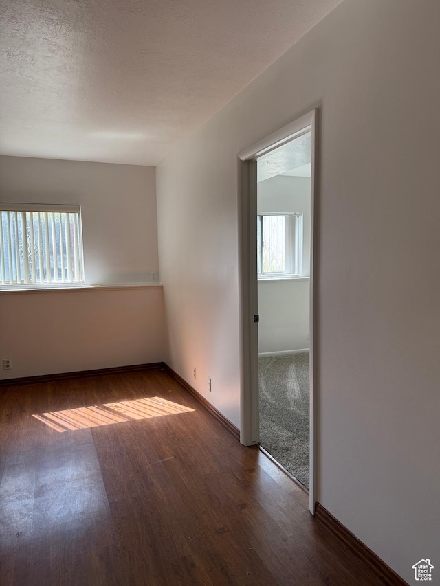 empty room with plenty of natural light, baseboards, and wood finished floors