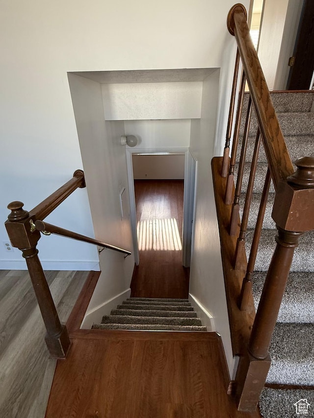 staircase featuring baseboards and wood finished floors