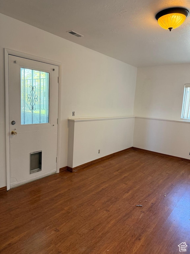 spare room featuring baseboards, wood finished floors, and visible vents