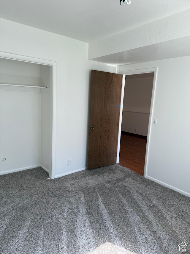 unfurnished bedroom featuring baseboards, carpet, and a closet