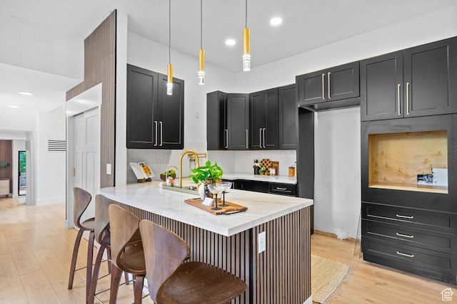 4758 S Ichabod St, Holladay, UT 84117 - kitchen featuring dark cabinets, light stone countertops, light wood-style floors, a kitchen bar, and recessed lighting