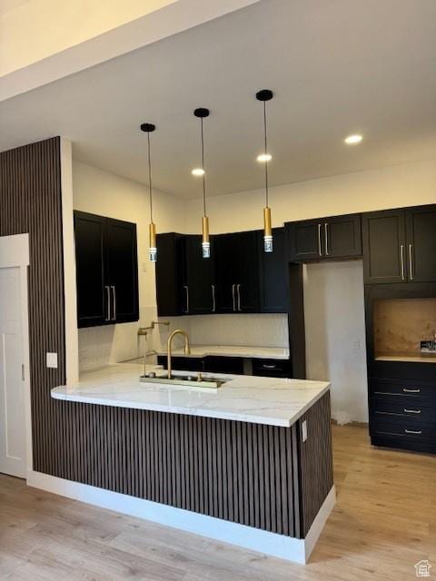 4758 S Ichabod St, Holladay, UT 84117 - kitchen with dark cabinetry, a peninsula, a sink, and light wood-style flooring