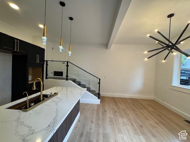 4758 S Ichabod St, Holladay, UT 84117 - kitchen with light stone counters, baseboards, a chandelier, dark cabinetry, and light wood-style flooring
