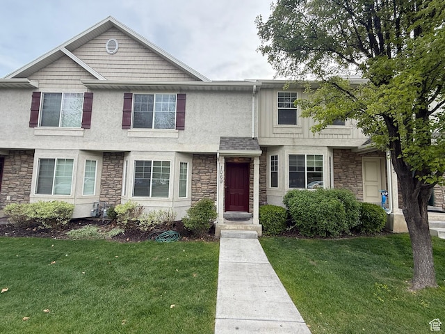 view of front of property featuring a front yard, stone siding, and stucco siding
