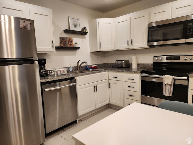 kitchen with light tile patterned flooring, open shelves, appliances with stainless steel finishes, a sink, and white cabinetry