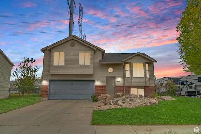 split foyer home with brick siding, a garage, a front yard, and concrete driveway