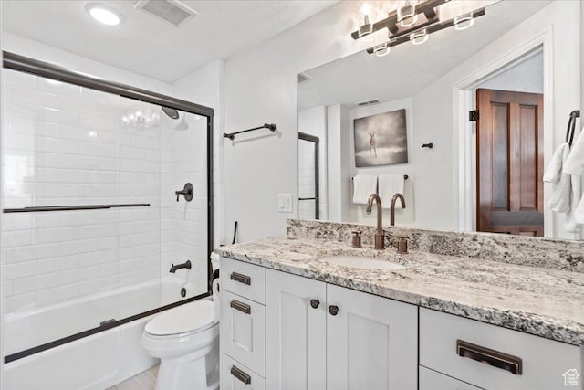 bathroom featuring toilet, visible vents, combined bath / shower with glass door, and vanity