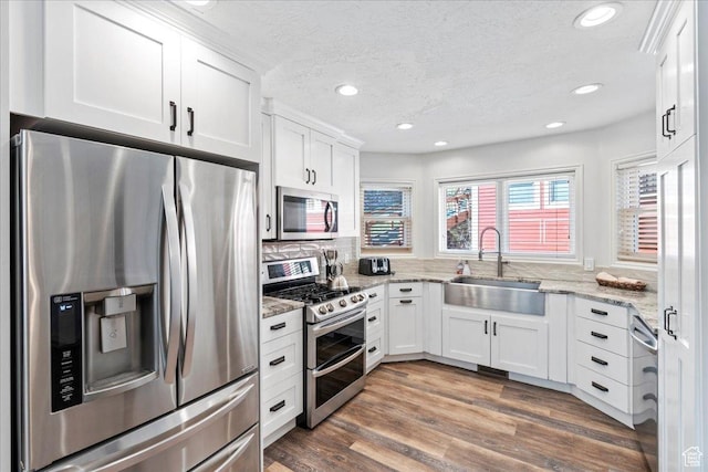 kitchen with recessed lighting, a sink, appliances with stainless steel finishes, and white cabinets