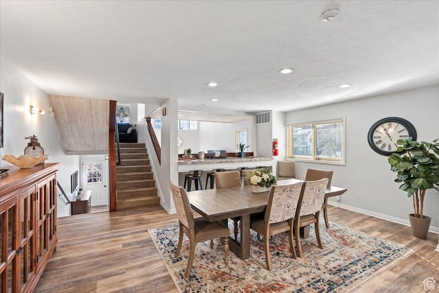 dining area featuring stairs, visible vents, plenty of natural light, and wood finished floors
