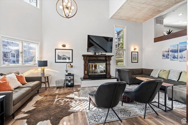 living room with visible vents, wood finished floors, a notable chandelier, and high vaulted ceiling