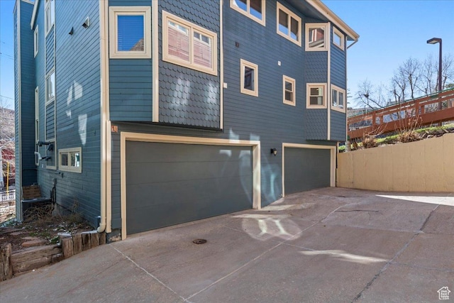 rear view of property featuring a garage, fence, and driveway