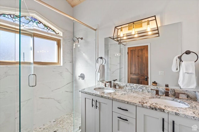 bathroom featuring double vanity, vaulted ceiling, a marble finish shower, and a sink