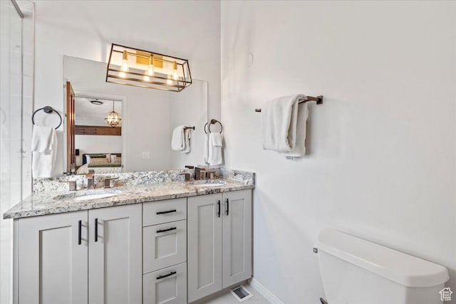 ensuite bathroom featuring a sink, double vanity, toilet, ensuite bathroom, and visible vents