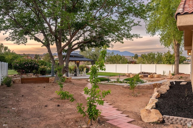 1864 S Crockett Cir, Bloomington, UT 84790 - yard at dusk featuring fence, a patio, a vegetable garden, a gazebo, and a mountain view