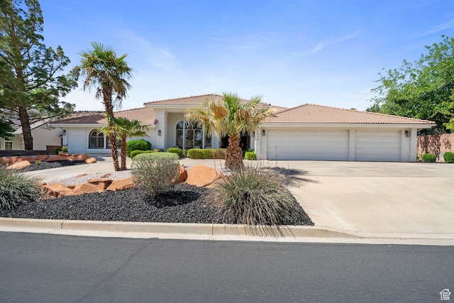 1026 Wesley Powell Dr, St George, UT 84790 - view of front facade featuring concrete driveway, an attached garage, a tile roof, and stucco siding
