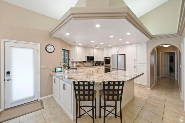 1026 Wesley Powell Dr, St George, UT 84790 - kitchen with arched walkways, stainless steel appliances, a peninsula, and light tile patterned flooring