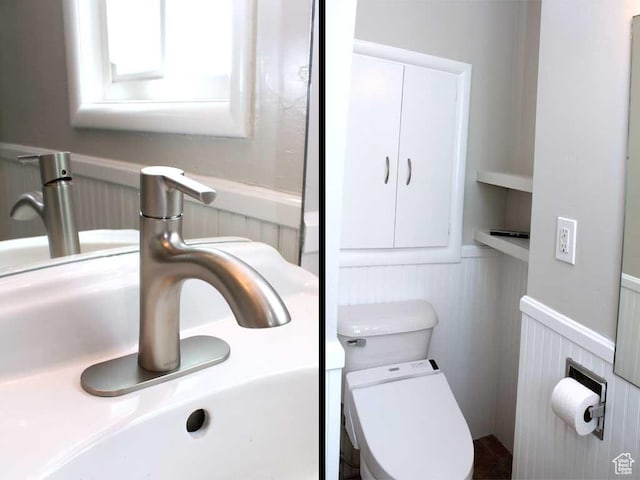 bathroom featuring a sink, wainscoting, and toilet