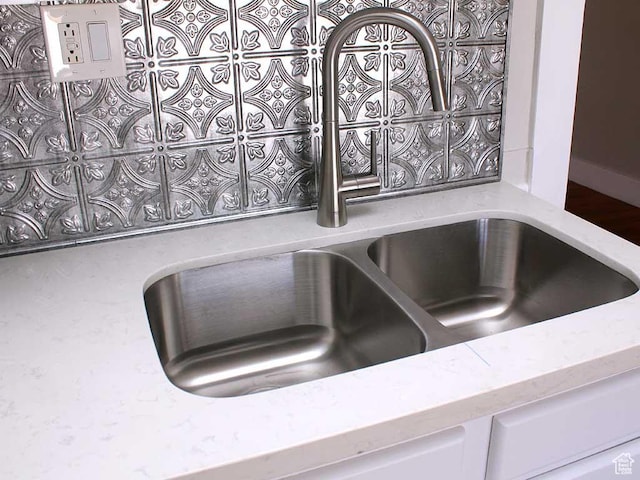 room details with a sink, light stone counters, and white cabinetry