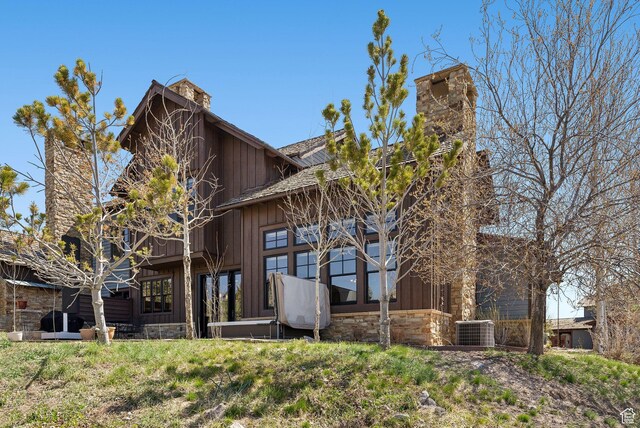 3250 E Thunderhawk Trl, Heber City, UT 84036 - back of property featuring board and batten siding, cooling unit, a chimney, and stone siding