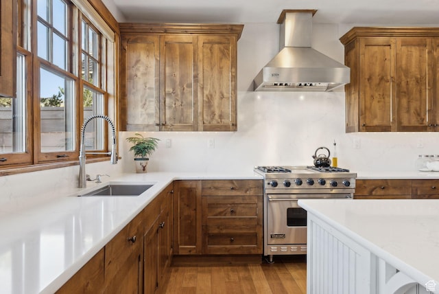 3250 E Thunderhawk Trl, Heber City, UT 84036 - kitchen featuring brown cabinetry, wood finished floors, luxury stove, wall chimney exhaust hood, and a sink